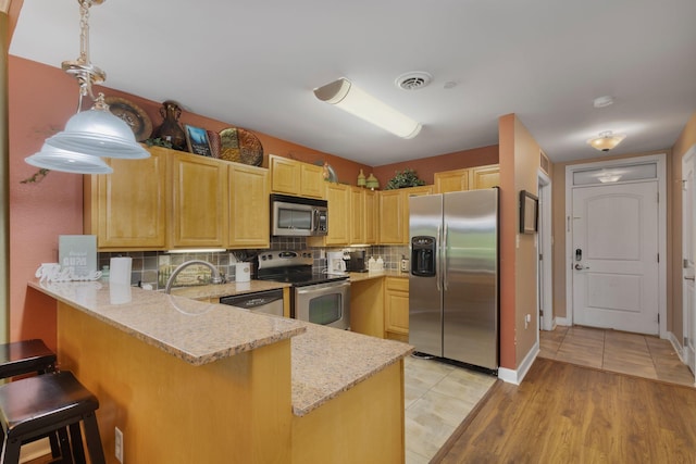 1410 Hurley Dr Unit 103, Sevierville, TN 37862 - kitchen featuring appliances with stainless steel finishes, a peninsula, light brown cabinets, and backsplash