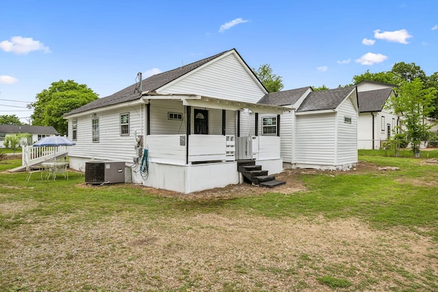 rear view of property featuring central air condition unit, a yard, a shingled roof, and covered porch