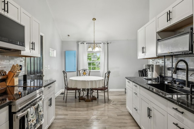 kitchen featuring appliances with stainless steel finishes, a sink, tasteful backsplash, vaulted ceiling, and white cabinets