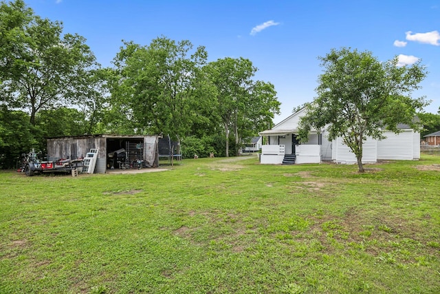 view of grassy yard featuring an outdoor structure, a trampoline, and a pole building