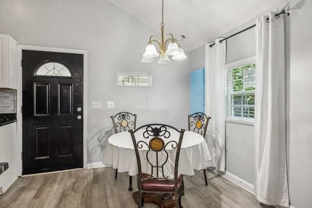 dining room with wood finished floors, a chandelier, baseboards, and vaulted ceiling