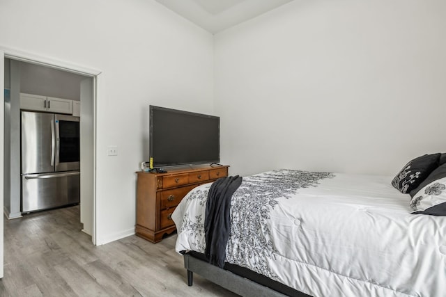bedroom featuring smart refrigerator, light wood-type flooring, baseboards, and vaulted ceiling