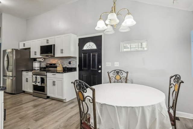 kitchen featuring appliances with stainless steel finishes, a chandelier, dark countertops, and tasteful backsplash