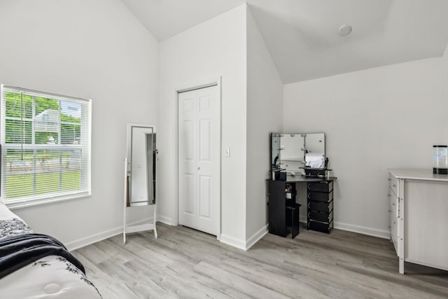 bedroom with light wood-style flooring, high vaulted ceiling, and baseboards