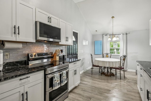kitchen featuring stainless steel appliances, vaulted ceiling, decorative backsplash, a chandelier, and white cabinetry