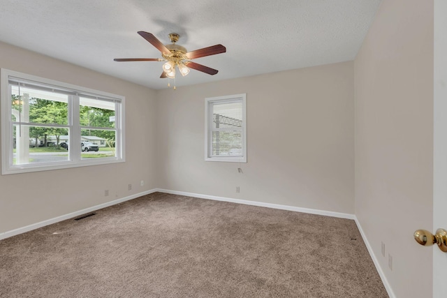 empty room with carpet floors, ceiling fan, baseboards, and a textured ceiling