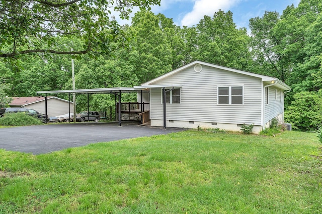 view of side of home featuring crawl space, asphalt driveway, a carport, and a lawn