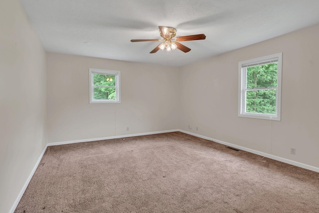 carpeted empty room with plenty of natural light, a ceiling fan, and baseboards