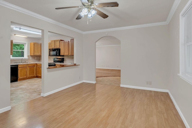 unfurnished living room featuring light wood-style flooring, ceiling fan, crown molding, arched walkways, and baseboards