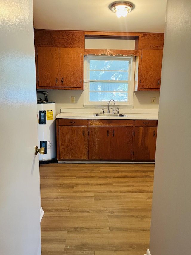 999 Mill St, Pulaski, TN 38478 - kitchen featuring electric water heater, brown cabinets, a sink, and light wood-style flooring