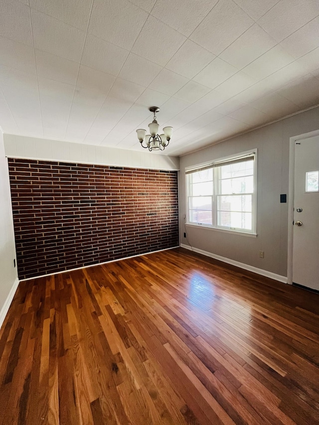 999 Mill St, Pulaski, TN 38478 - unfurnished dining area featuring wood finished floors, a chandelier, baseboards, and brick wall