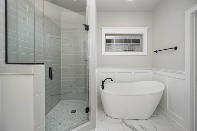 2024 Kestrel Ln, Spring Hill, TN 37174 - full bathroom with marble look tile flooring, a stall shower, a freestanding bath, a wainscoted wall, and a decorative wall