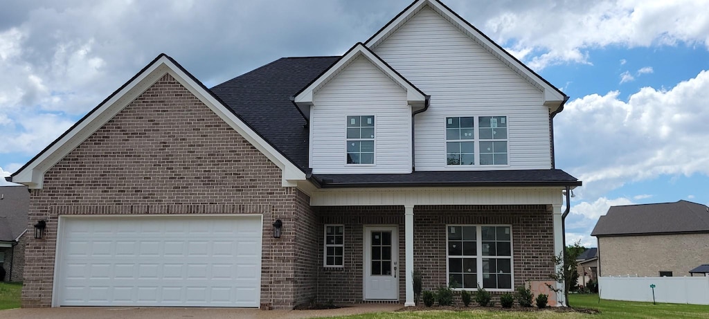 view of front facade with brick siding, driveway, covered porch, and an attached garage