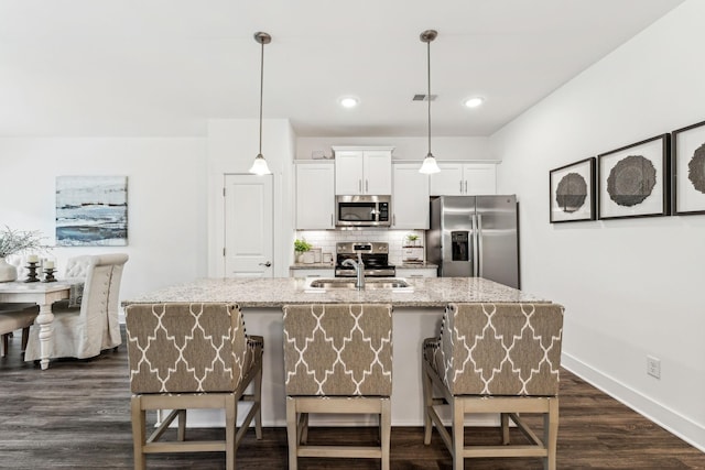 1115 Sweetleaf Dr, Franklin, TN 37064 - kitchen with stainless steel appliances, a sink, light stone countertops, decorative backsplash, and a breakfast bar area