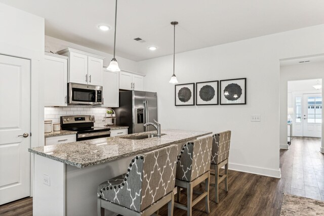 1115 Sweetleaf Dr, Franklin, TN 37064 - kitchen with appliances with stainless steel finishes, a sink, decorative backsplash, dark wood-type flooring, and a kitchen bar