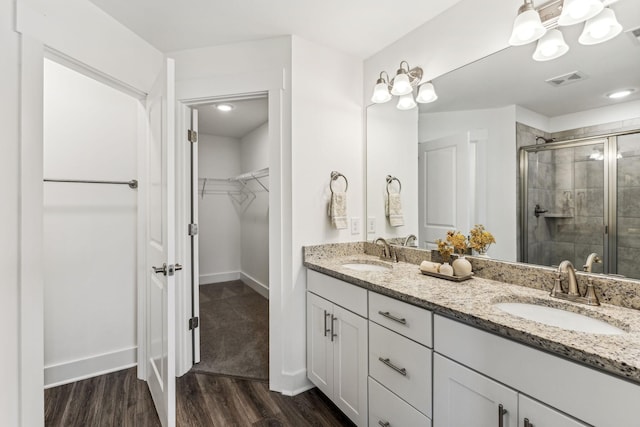 1115 Sweetleaf Dr, Franklin, TN 37064 - bathroom featuring a stall shower, a walk in closet, wood finished floors, double vanity, and baseboards