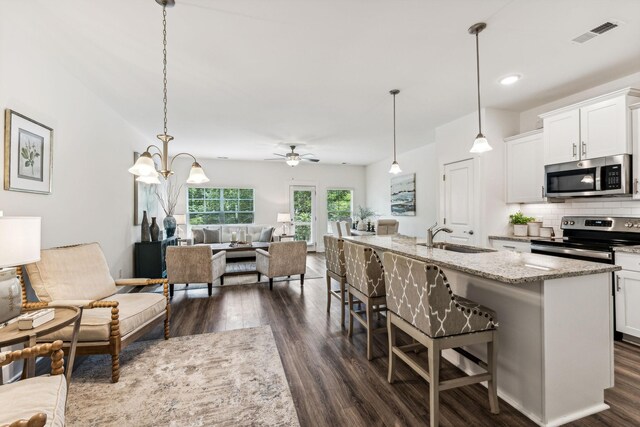 1115 Sweetleaf Dr, Franklin, TN 37064 - kitchen featuring stainless steel appliances, a sink, open floor plan, dark wood-style flooring, and a breakfast bar area