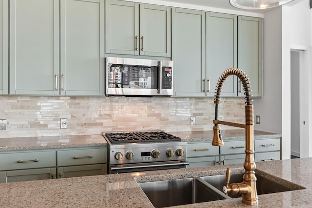 1212 Laurel St Unit 701, Nashville, TN 37203 - kitchen with stainless steel appliances, green cabinets, light stone counters, and decorative backsplash
