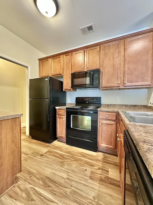 8501 Burnham Ln Unit 6, Antioch, TN 37013 - kitchen with black appliances, light wood-type flooring, brown cabinetry, a sink, and light countertops