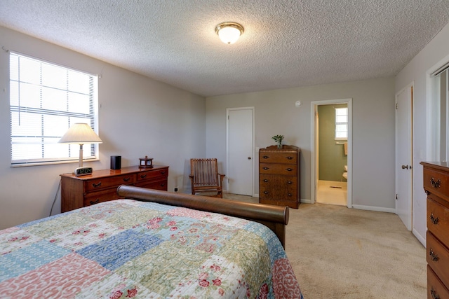 bedroom featuring a textured ceiling, light carpet, and connected bathroom