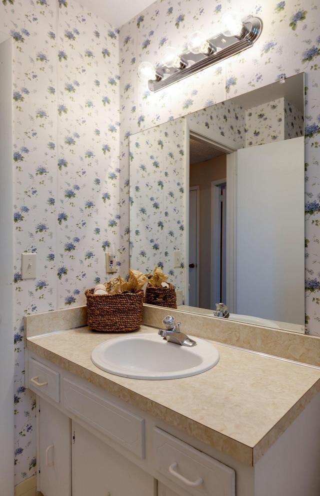 bathroom featuring wallpapered walls and vanity