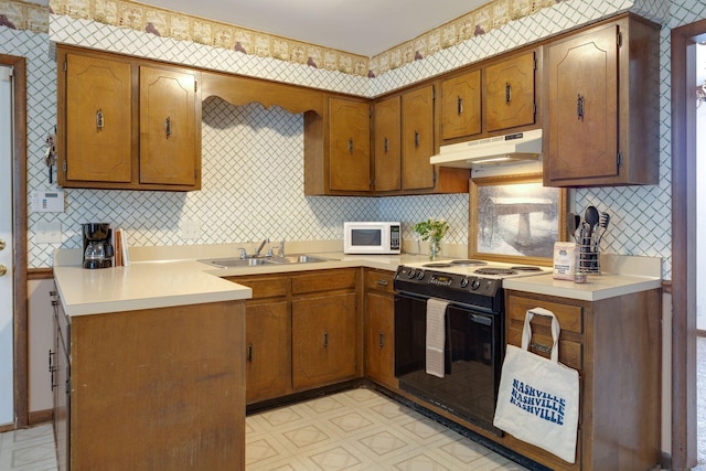 kitchen with electric range, a sink, under cabinet range hood, white microwave, and brown cabinetry