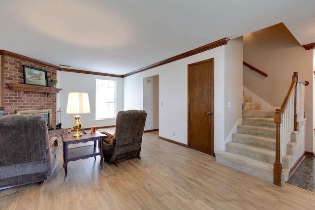 living room featuring light wood finished floors, stairway, crown molding, baseboards, and a fireplace