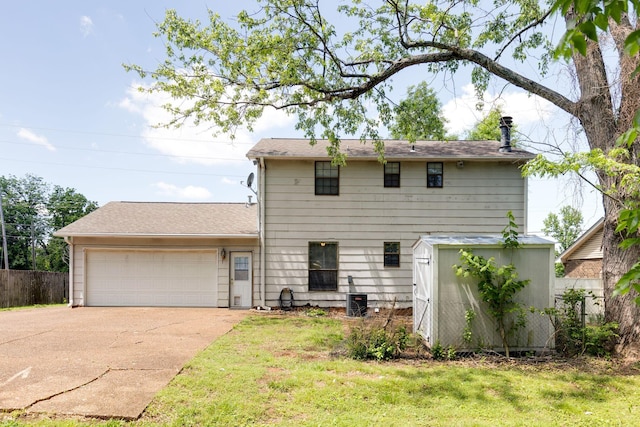back of property featuring an attached garage, driveway, and a storage shed