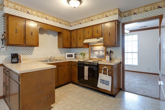 kitchen featuring white appliances, under cabinet range hood, light floors, a sink, and baseboards