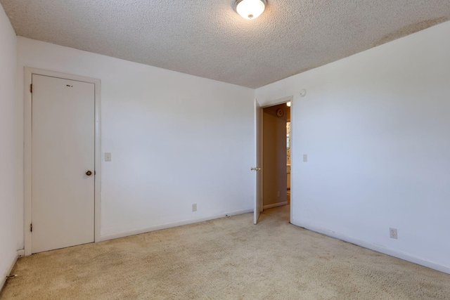 carpeted spare room featuring a textured ceiling and baseboards