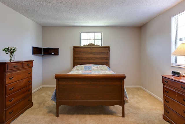 bedroom featuring light colored carpet, a textured ceiling, and baseboards