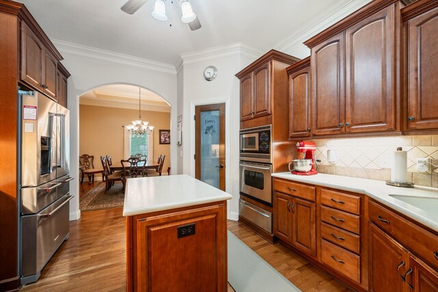 575 Homestead Ln, Henderson, TN 38340 - kitchen with appliances with stainless steel finishes, a warming drawer, arched walkways, wood finished floors, and crown molding