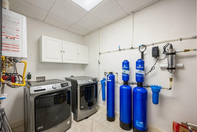 575 Homestead Ln, Henderson, TN 38340 - washroom with washing machine and dryer, tankless water heater, cabinet space, light tile patterned floors, and baseboards