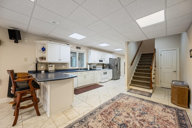 575 Homestead Ln, Henderson, TN 38340 - kitchen with white appliances, dark countertops, a peninsula, open shelves, and white cabinetry