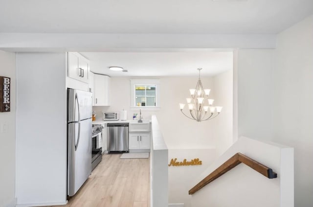 1822 Jefferson St, Nashville, TN 37208 - kitchen with stainless steel appliances, white cabinetry, light wood finished floors, light countertops, and a chandelier