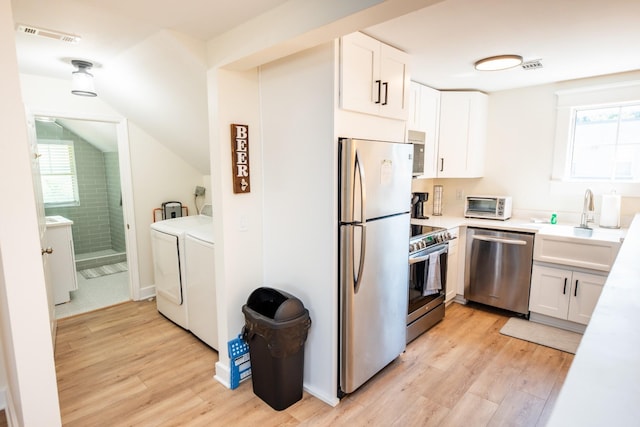 1822 Jefferson St, Nashville, TN 37208 - kitchen with stainless steel appliances, washer and clothes dryer, light wood-style floors, white cabinetry, and vaulted ceiling