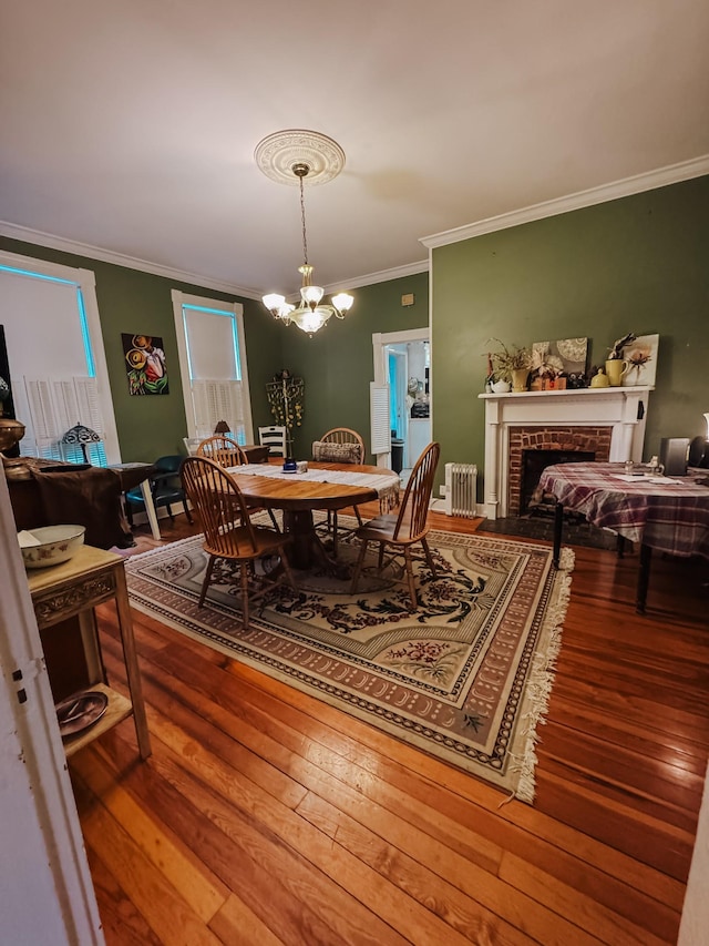 209 Main St, Cumberland City, TN 37050 - dining room with radiator heating unit, ornamental molding, hardwood / wood-style flooring, a chandelier, and a fireplace