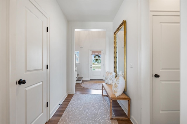 entryway with dark wood finished floors, baseboards, and stairway