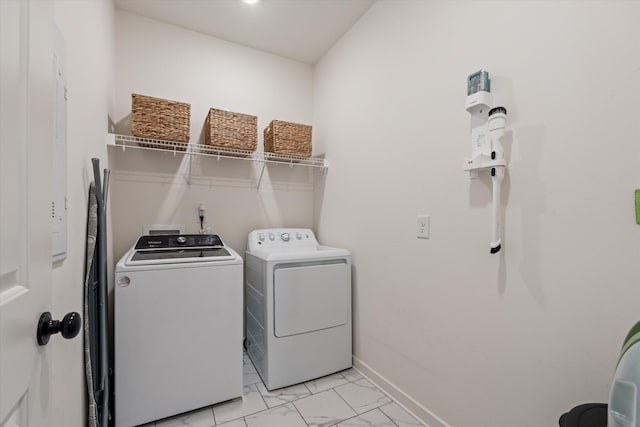 laundry area with washing machine and dryer, light marble finish flooring, and baseboards
