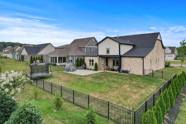 rear view of house with a trampoline, a patio, brick siding, and a residential view