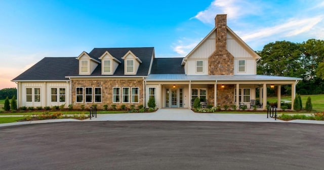 view of front of home featuring stone siding, a porch, a chimney, and board and batten siding