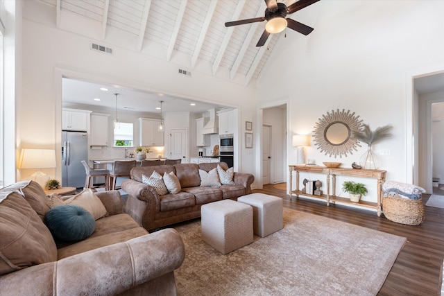 living room featuring ceiling fan, high vaulted ceiling, dark wood-type flooring, beam ceiling, and recessed lighting