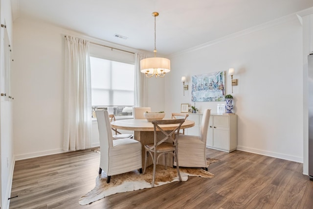 dining area featuring light wood-style floors, a chandelier, baseboards, and ornamental molding