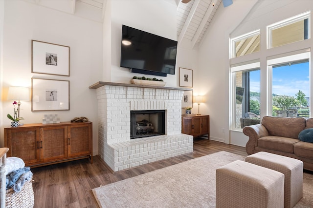 living room featuring high vaulted ceiling, wood finished floors, a fireplace, baseboards, and beamed ceiling