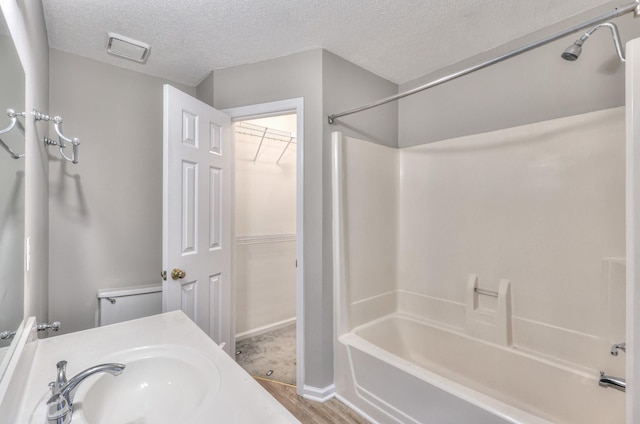 1716 Golden Valley Dr, Christiana, TN 37037 - bathroom with a textured ceiling, bathing tub / shower combination, a walk in closet, wood finished floors, and baseboards