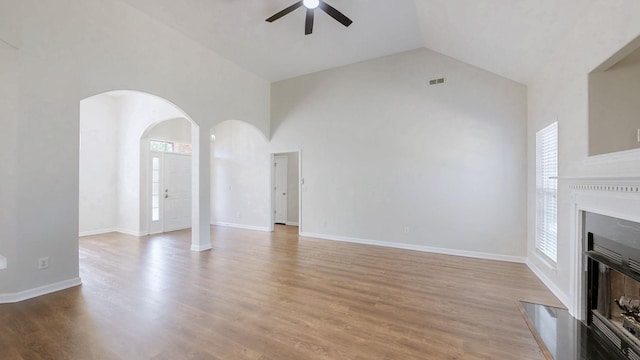 2014 Patrick Way, Spring Hill, TN 37174 - unfurnished living room featuring ceiling fan, a glass covered fireplace, high vaulted ceiling, arched walkways, and wood finished floors