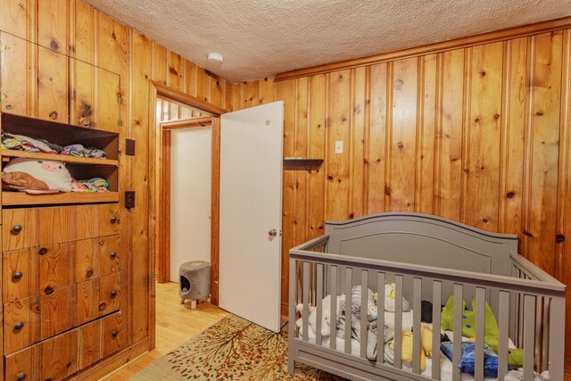 3913 Pickering Ave, Chattanooga, TN 37415 - bedroom featuring a textured ceiling, wood finished floors, wooden walls, and a crib