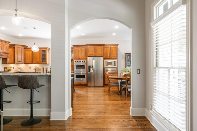 109 Allenhurst Cir, Franklin, TN 37067 - kitchen featuring appliances with stainless steel finishes, arched walkways, brown cabinetry, light stone countertops, and crown molding