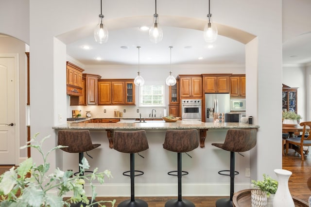 109 Allenhurst Cir, Franklin, TN 37067 - kitchen with stainless steel appliances, brown cabinets, arched walkways, light stone countertops, and a peninsula