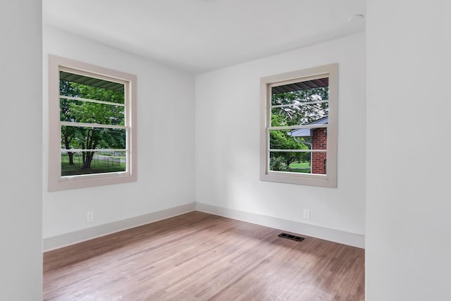 unfurnished room featuring plenty of natural light, wood finished floors, and baseboards